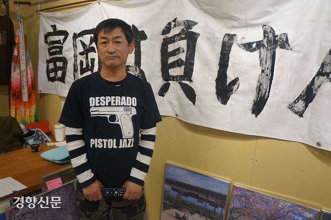 일본의 지역 활동가 히라야마 쓰토무가 지난달 26일 후쿠시마현 후타바군 도미오카 마을의 ‘후타바인포’에서 ‘도미오카는 지지 않는다’는 플래카드를 배경으로 현지 상황을 설명하고 있다.  후타바 | 김진우 특파원