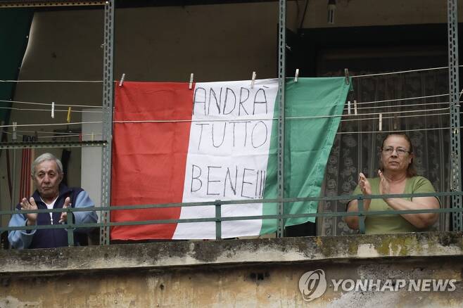 발코니서 코로나19 응원 박수치는 이탈리아인들 (밀라노 AP=연합뉴스) 14일(현지시간) 정오 이탈리아 로마에 사는 한 부부가 집 발코니에 '모든 것이 다 잘 될 거야'(Andra tutto bene)라는 글귀를 적은 국기를 걸어놓고 코로나19와 사투를 벌이는 의료진을 응원하는 의미로 박수를 치고 있다. leekm@yna.co.kr