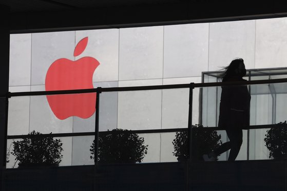 애플은 아이폰의 90%를 중국에서 생산하고 있지만 앞으로 15~30%를 중국 외 지역에서 생산하는 방안을 추진하고 있다. 지난해 12월 중국 베이징에서 한 여성이 애플 로고가 그려진 건물 앞을 지나고 있다. [연합뉴스]