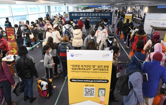 중국과 홍콩, 마카오에 대한 특별입국절차가 개시된 2월 13일 인천국제공항에서 홍콩 발 항공편 승객들이 '자가진단 앱' 설치를 위해 줄지어 서 있다. [연합뉴스]