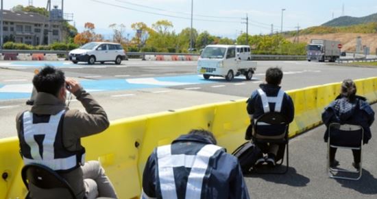 일본 도쿠시마현 직원들이 한 도로 나들목에서 쌍안경을 이용해 지역으로 유입되는 차량번호를 조사하고 있다. 아사히신문 홈페이지 캡처