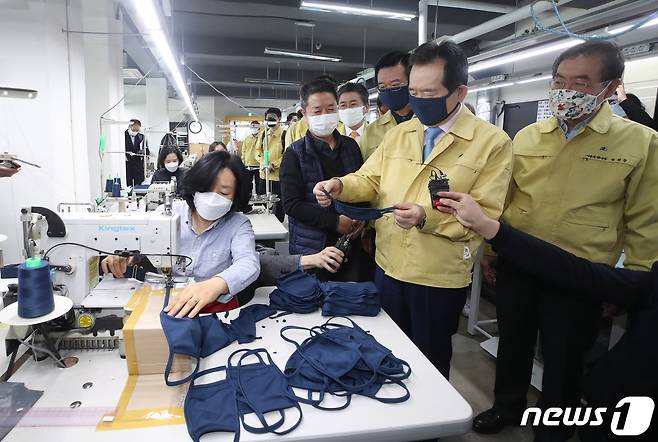 정세균 국무총리가 박원순(오른쪽) 서울시장과 함께 25일 오전 서울 용산구 만리시장 내 한국패션봉제협회 교육장인 코워킹팩토리를 찾아 필터교체형 면마스크인 '서울형 마스크' 생산 현장을 둘러보고 있다. 오른쪽 세번째는 이상태 한국패션봉제협회장. 2020.3.25/뉴스1 © News1 이동해 기자