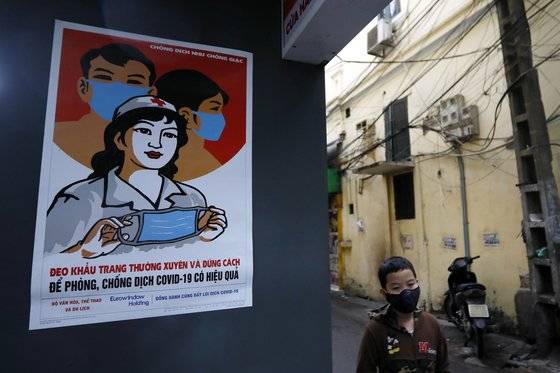 베트남 수도 하노이에 지난달 24일 마스크 사용을 권장하는 벽보가 붙어있는 옆으로 어린이가 마스크를 쓴 채 지나고 있다. EPA=연합뉴스