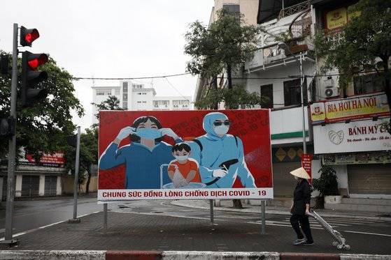 배트남의 이동 제한령이 해제된 23일 수도 하노이에서 주민이 마스크 착용을 권장하는 공산당 선전 입간판 앞을 지나고 있다. 이런 종류의 공산당 선전 입간판은 베트남 전쟁 당시 많이 보였다가 서서히 줄었는데, 코로나19가 유행하면서 다시 등장하고 있다. EPA=연합뉴스