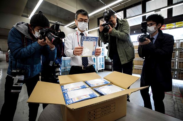 일본 도쿄의 한 우체국 직원이 지난달 16일 주민들에게 배포될 이른바 ‘아베노 마스크’를 들어 보이며 기자들 앞에서 포즈를 취하고 있다. 도쿄=AFP 연합뉴스