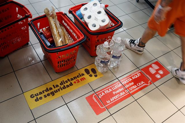 스페인 론다의 한 슈퍼마켓에서 6일 한 고객이 코로나19 확산방지를 위해 '2m 거리를 유지하라'는 내용이 적힌 스티커 앞을 지나가고 있다. 론다=로이터 연합뉴스