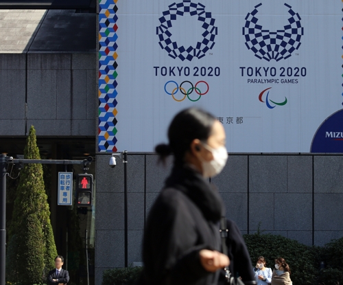 마스크를 쓴 여성이 지난 3월 9일 오후 도쿄 올림픽·패럴림픽 홍보물이 설치된 일본 도쿄도(東京都) 지요다(千代田)구의 한 사거리를 지나가고 있다. 도쿄올림픽은 2021년으로 1년 연기됐다.  ｜연합뉴스