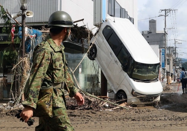 일본 자위대원이 망가진 자동차를 바라보며 지나가고 있다. [사진=EPA 연합뉴스]