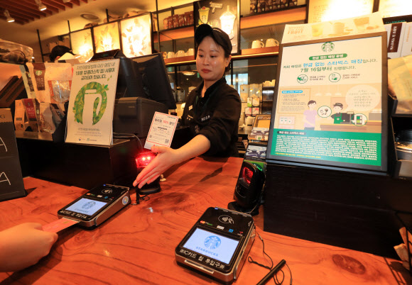 서울시내의 한 스타벅스 매장에서 직원이 고객에게 디지털 결제수단 이용을 안내하고 있다. 스타벅스코리아는 2018년부터 전국의 주요 매장에서 ‘현금 없는 매장’ 운영을 시작했다.연합뉴스