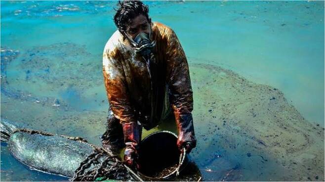 일본 화물선 '와카시오'호 기름 유출 사고로 모리셔스 해안이 오염된 가운데 한 남성이 방제작업을 하는 모습.(사진=연합뉴스)