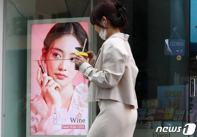 서울 명동의 문 닫은 화장품 가게 앞을 한 시민이 답답함에 마스크를 턱에 걸쳐둔 채 지나가고 있다./뉴스1 © News1 이동해 기자
