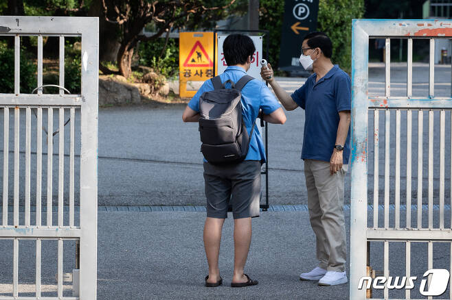 수도권 지역 전면 원격수업이 시행된 지난 26일 서울시내 한 고등학교에서 한 고3 학생이 등교하며 발열체크를 받고 있다. 6/뉴스1 © News1 유승관 기자