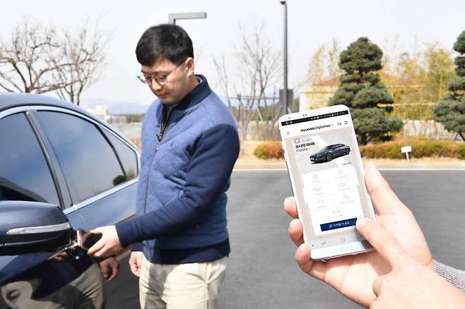 원거리에서 스마트폰 통해 자동차의 문을 열고 있다.