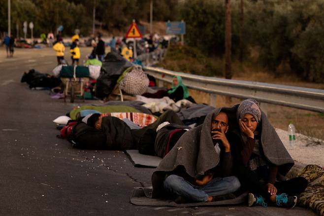 11일(현지시간) 그리스 레스보스섬의 모리아 난민캠프 인근 도로 위에서 난민들이 담요를 덮고 망연자실해 있다. 레스보스｜로이터연합뉴스