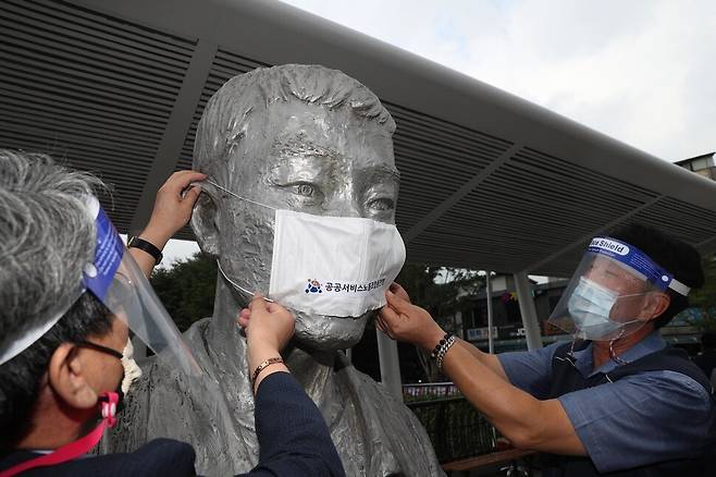 16일 오전 서울 종로구 전태일다리에서 열린 ‘제16차 전태일 50주기 캠페인’에서 참석자들이 전태일 동상에 마스크를 씌우고 있다. 김봉규 선임기자