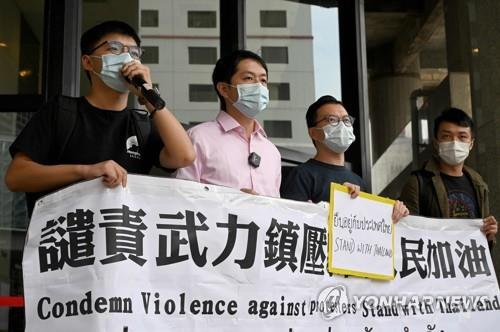 조슈아 웡(왼쪽) 등 홍콩 민주화 활동가들이 19일 홍콩 주재 태국 영사관이 입주한 건물 앞에서 태국 반정부 시위대에 연대를 표하는 배너를 들고 서 있는 모습. [AFP=연합뉴스]