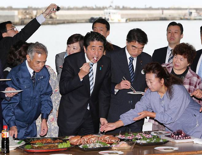 지난 2013년 아베 신조 전 일본 총리가 후쿠시마산 수산물이 안전하다 주장하며 직접 먹어 보이고 있다(사진=AFP)