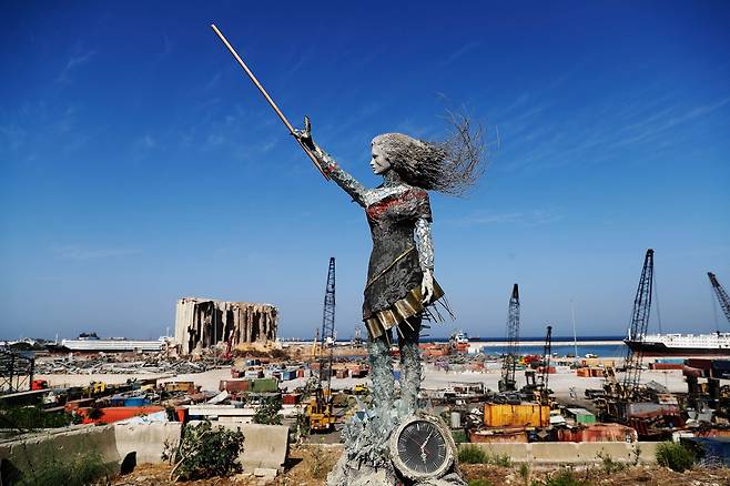 20일(현지시간) 복구 작업이 한창인 레바논 베이루트 항구에 여성 동상이 세워져 있다. 레바논 예술가들은 폭발이 있었던 지난 8월 4일 오후 6시 7분에 멈춘 시계와 폭발 현장의 파편 등으로 이 동상을 만들었다. AFP=연합뉴스