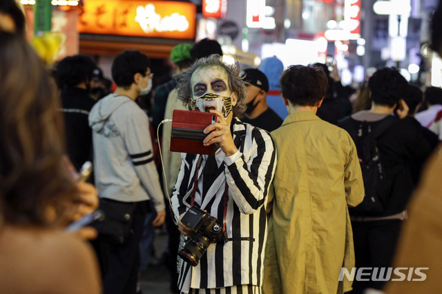 [도쿄=AP/뉴시스]10월 31일 저녁 일본 도쿄의 시부야 거리에서 핼러윈 분장을 한 한 남성이 사진을 찍고 있다. 이날 시부야 거리에 핼러윈을 즐기려는 수천 명이 몰려들었으며 시 당국은 코로나19 확산 우려로 사람들에게 모이지 말 것을 요청했다. 2020.11.01.