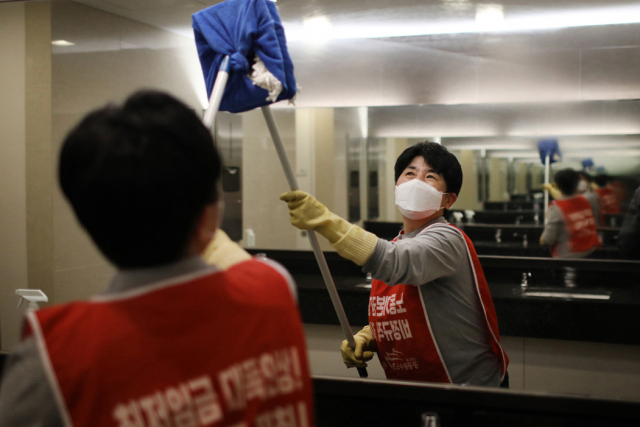 ▲ 빨간 몸자보를 입고 화장실 거울을 닦고 있는 LG트윈타워 청소노동자. ⓒ프레시안(최형락)