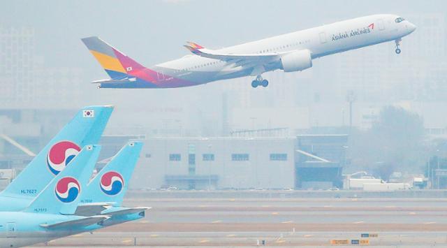 18일 인천국제공항 주기장에 세워진 대한항공 여객기 뒤로 아시아나항공기가 이륙하고 있다. 연합뉴스