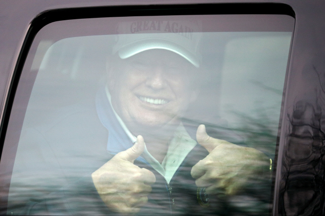 도널드 트럼프 미국 대통령이 22일(현지시간) 버지니아주 스털링의 트럼프 내셔널 골프클럽으로 이동하다가 차 안에서 지지자들을 향해 미소지으며 양 엄지손가락을 치켜들고 있다. /로이터연합뉴스