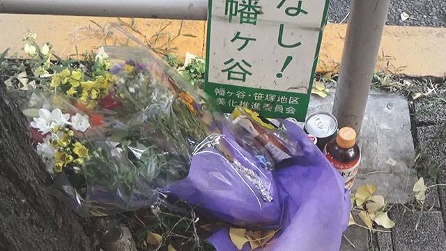 女性路宿人が死んだバス停に置かれた花束と飲み物たち. 〈日本 NHK 放送画面〉