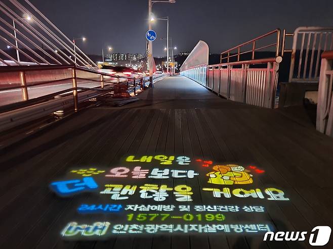 시천교로 들어서는 입구 바닥에 자살 예방을 당부하는 로고 라이트가 투사되고 있다. © 뉴스1