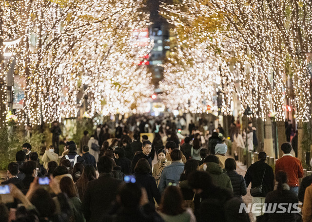 [도쿄=AP/뉴시스]크리스마스 전날인 24일 일본 도쿄의 한 거리에서 시민들이 나무에 장식된 조명을 휴대폰으로 촬영하고 있다. 이날 일본의 신종 코로나바이러스 감염증(코로나19) 신규 확진자 수는 최다를 기록했다. 2020.12.24.