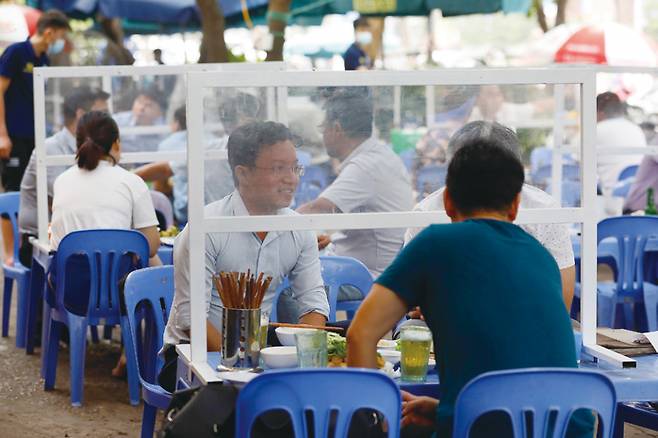 베트남 하노이의 한 식당에서 주민들이 플라스틱으로 만든 투명 가림막을 사이에 두고 점심을 먹고 있다. ⓒEPA 연합