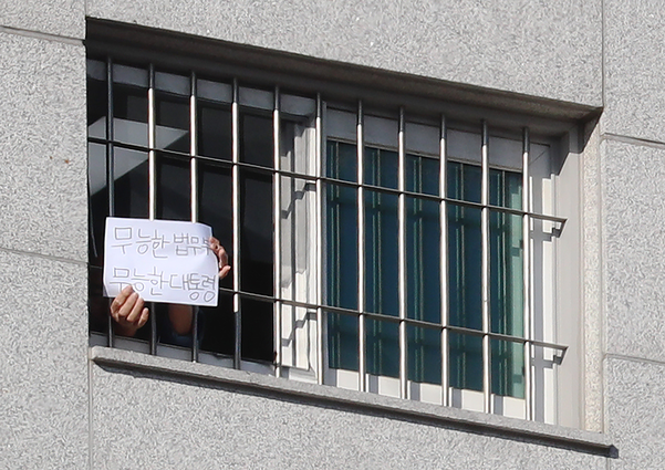 6일 오후 서울 송파구 동부구치소에서 한 수용자가 '무능한 법무부 무능한 대통령'이라고 쓴 종이를 창문 밖에 보이고 있다./연합뉴스