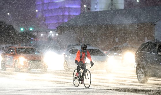 연일 한파가 이어지며 눈이 내리고 있는 6일 오후 서울 종로구 광화문네거리에서 한 시민이 자전거를 타고 이동하고 있다. 뉴시스