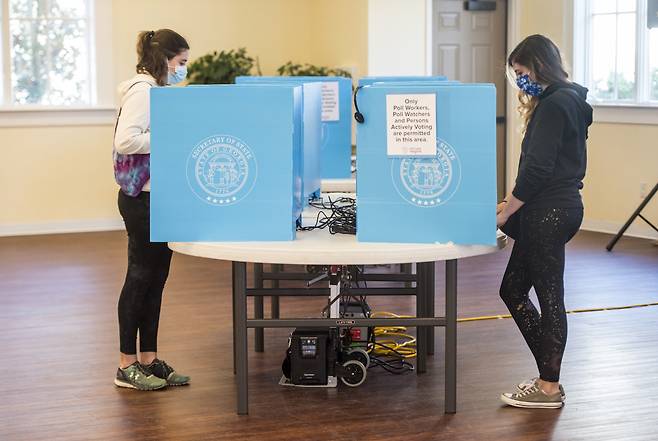 미 조지아주 상원 결선투표가 5일(현지시간) 진행 중인 가운데 유권자들이 마스크를 쓴 채 투표하고 있다.[AP]