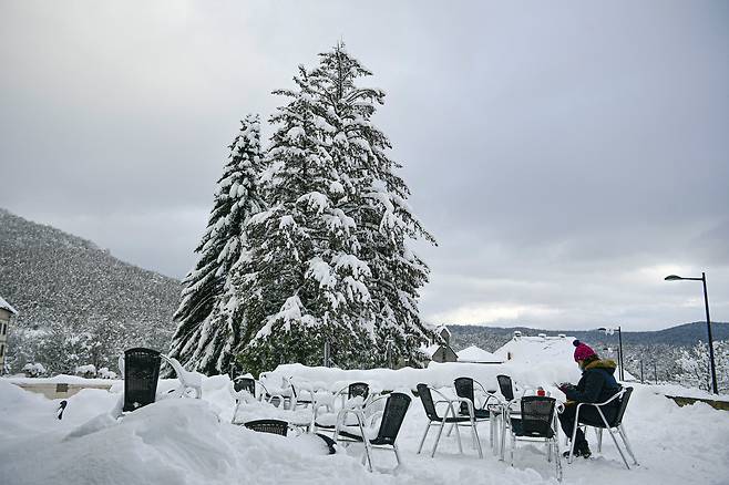 지난 5일(현지 시각) 스페인 론세스바예스에서 한 여성이 눈 내린 야외 식탁에서 점심을 먹고 있다. /AP 연합뉴스
