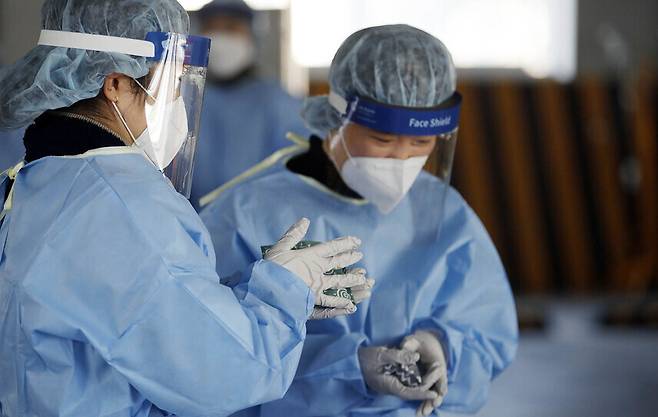Medical workers at a screening center in Gwangju warm their hands amid freezing temperatures on Jan. 6. (Yonhap News)