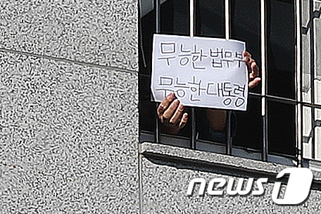 6일 오후 서울 송파구 동부구치소에서 한 재소자가 '무능한 법무부, 무능한 대통령'이라는 문구가 적힌 종이를 창살 너머로 꺼내 보이고 있다. 2021.1.6/뉴스1 © News1 민경석 기자