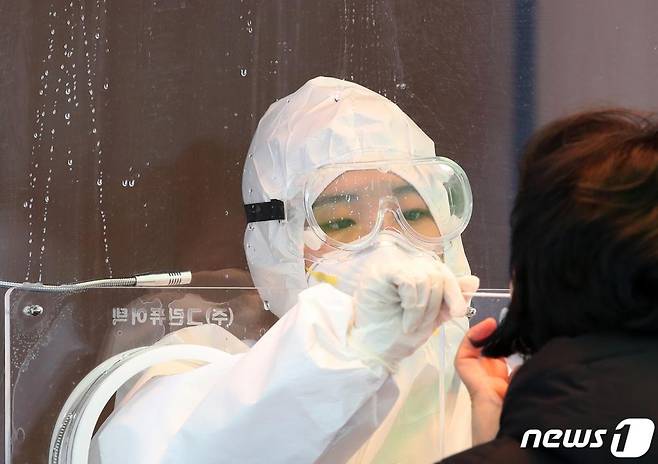 (서울=뉴스1) 오대일 기자 = '북극한파'가 이어진 8일 서울 용산구 서울역에 마련된 신종 코로나 바이러스 감염증(코로나19) 임시 선별진료소에서 의료진이 시민의 검체를 채취하고 있다. 진료소 창문에 전날 쌓인 눈이 녹아 흘러내리고 있다. 이날 0시 기준 국내 코로나19 신규 확진자는 674명으로 전일 870명 대비 196명 감소했다. 2021.1.8/뉴스1