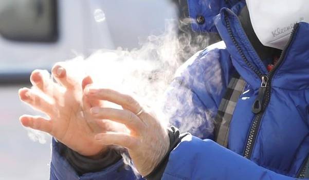 지난 8일 오전 서울역광장 임시선별진료소에서 한 시민이 손 소독을 하자 강추위에 김이 나고 있다. /연합뉴스