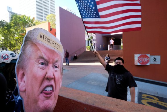 미국 캘리포니아주 로스앤젤레스(LA)에서 9일(현지시간) 도널드 트럼프 대통령 반대 시위대가 내건 풍자 사진 앞에서 트럼프 대통령 지지자가 미국 국기를 흔들며 대치하고 있다. 사진=로이터뉴스1