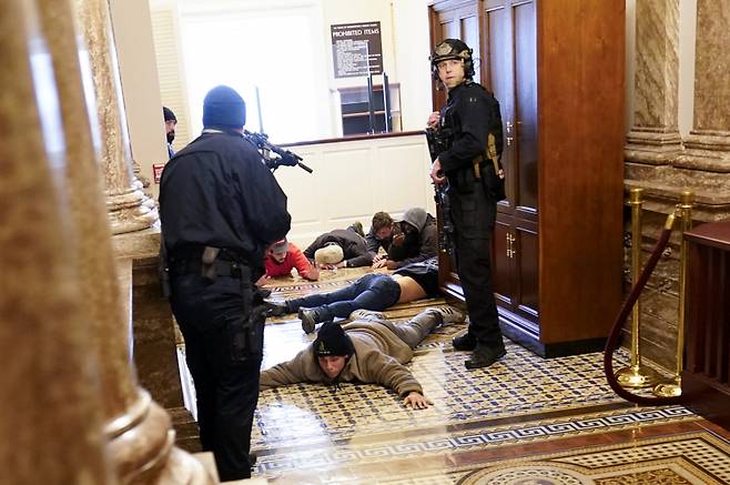 미 의회 경찰이 1월6일(현지 시각) 워싱턴DC 연방 의사당 내 하원 본회의장에 침입한 시위대를 엎드리게 한 후 총을 겨누고 있다. ⓒ AP 연합