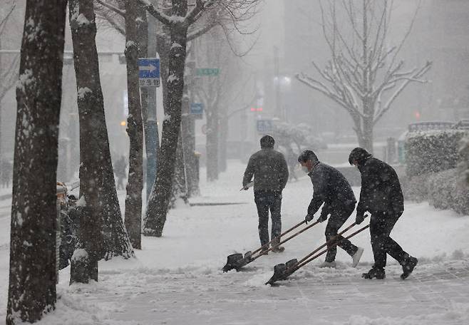 서울에 눈이 내린 12일 오후 정부서울청사 인근 도로에서 한 건물 직원들이 눈을 치우고 있다. (사진=연합뉴스)