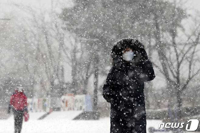 서울 동남·서남권, 경기도 광명·시흥에 대설주의보가 발효된 12일 오후 서울 송파구 롯데월드타워 인근에서 시민들이 발걸음을 재촉하고 있다. 2021.1.12/뉴스1 © News1 이승배 기자