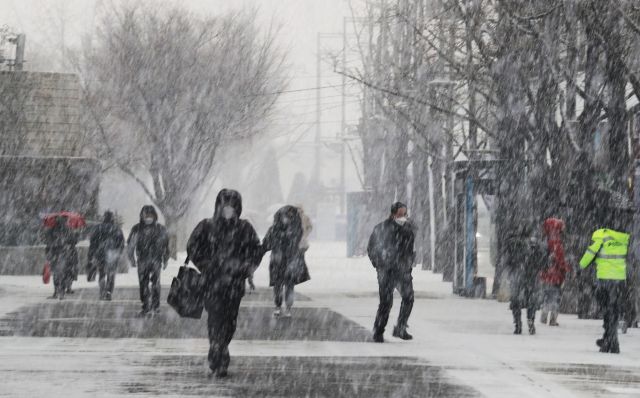 12일 눈이 내리는 서울 광화문 거리에서 시민들이 조심조심 발걸음을 옮기고 있다. 연합뉴스