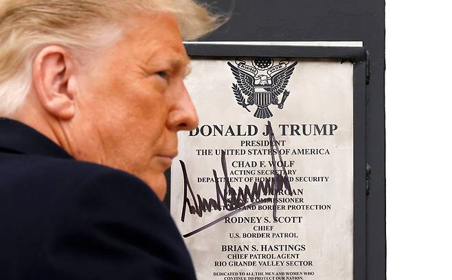 트럼프 미국 대통령이 12일 멕시코 국경장벽 완성지역을 방문해 자신의 이름이 새겨진 명판에 사인하고 있다. 로이터=연합뉴스