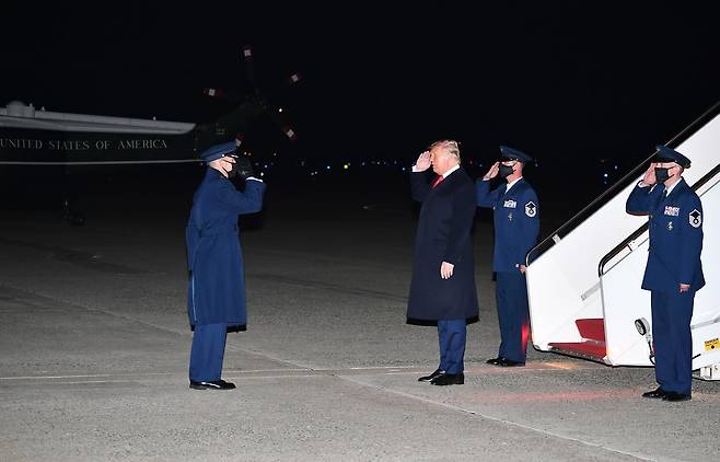 국경장벽 방문을 마치고 앤드류스 공군기지에 도착한 트럼프 대통령이 공군 1호기에서 내려 헬기로 갈아타기에 앞서 공군관계자의 경례에 답하고 있다. AFP=연합뉴스
