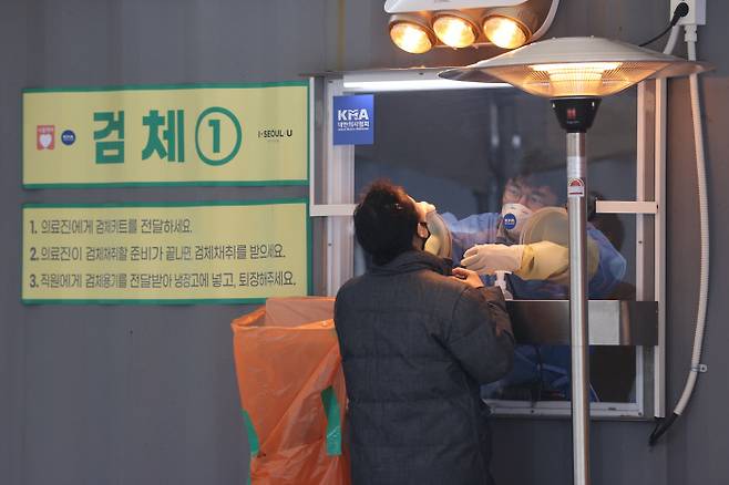 의료인이 13일 오전 서울시청 앞 임시선별검사소에서 한 시민의 검체를 채취하고 있다. 연합뉴스