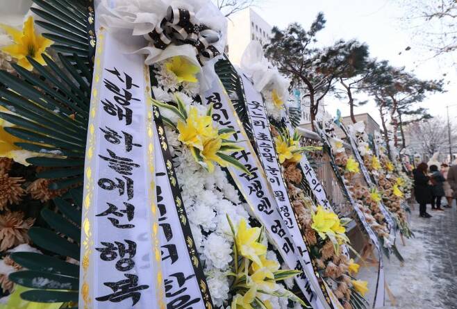 A row of funeral wreaths made of white and yellow flowers is laid alongside the wall of the Seoul Southern District Court on Wednesday. (Yonhap)