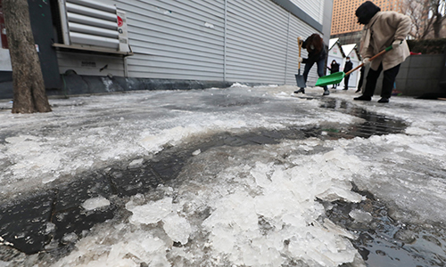 지난 12일 서울 종로구 일대에서 시민들이 비교적 포근해진 날씨로 인해 녹기 시작한 얼음을 제거하고 있다. 뉴스1
