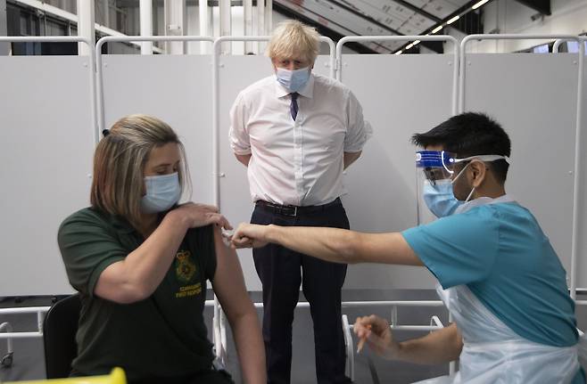 보리스 존슨(가운데) 영국 총리가 11일(현지 시각) 런던 남서부 브리스틀의 애슈턴 게이트 스타디움에 설치된 코로나 백신 센터에서 한 여성이 백신 접종 받는 모습을 지켜보고 있다. /AP 연합뉴스