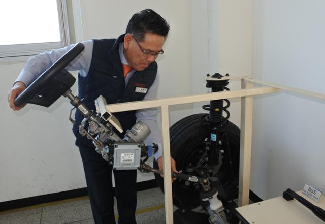 김홍근 회장이 모형 자동차 운전대에 자사의 조향장치를 설치 과정을 보여주고 있다.